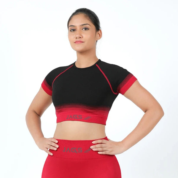 A woman wearing a red and black sports crop top and leggings, with the brand logo visible on the crop top.